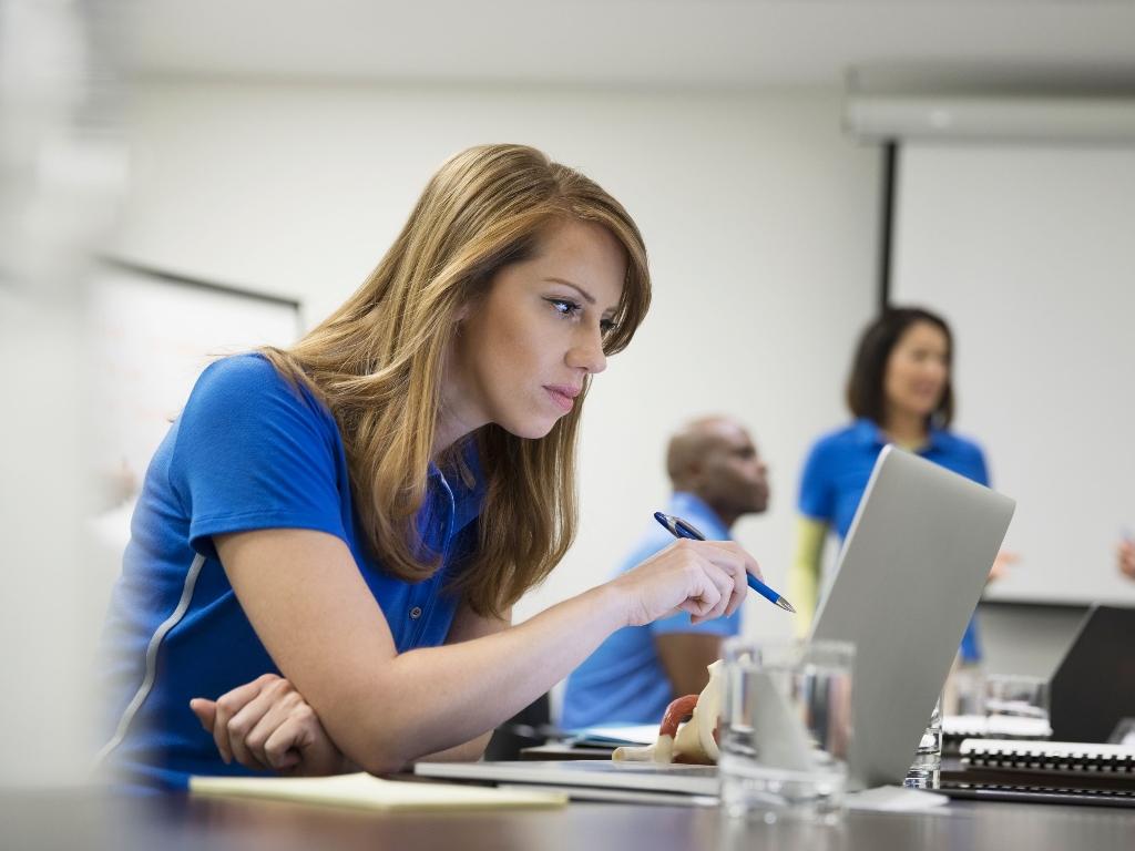Healthcare professional reviewing training materials and product documentation on a laptop during a support session