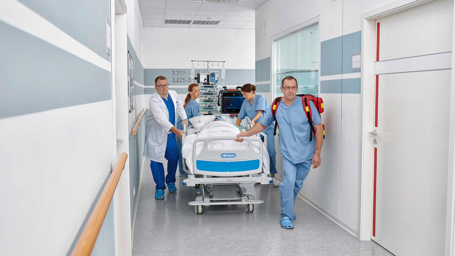 Staff move an ICU patient bed along a hospital hallway