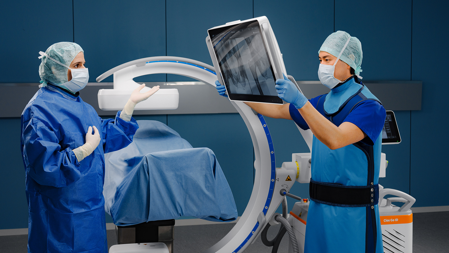 Surgeon positioning the integrated display of the Cios Go ID for comfortable image viewing during a procedure.