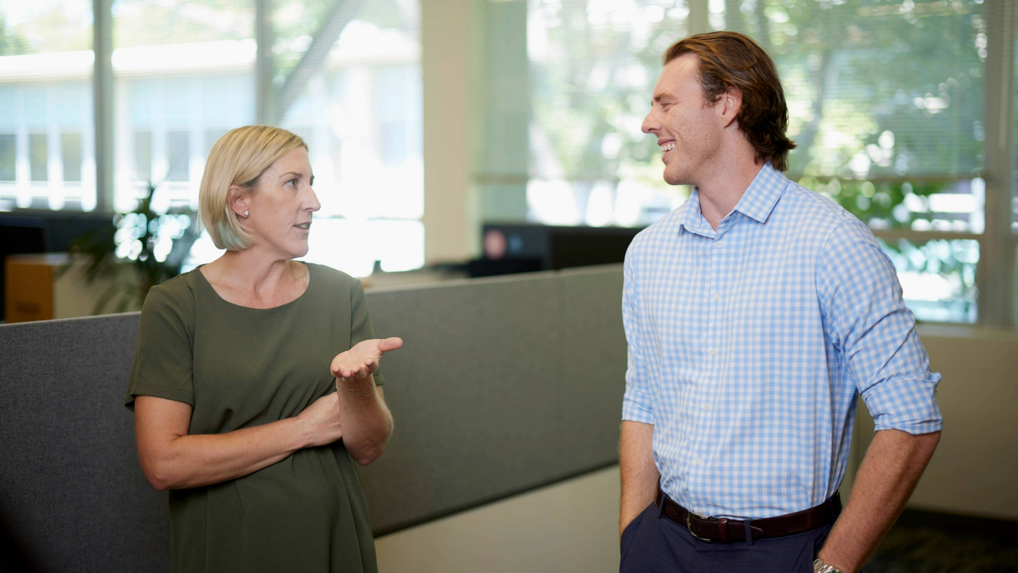 Eine Frau und ein Mann diskutieren in einem Großraumbüro.