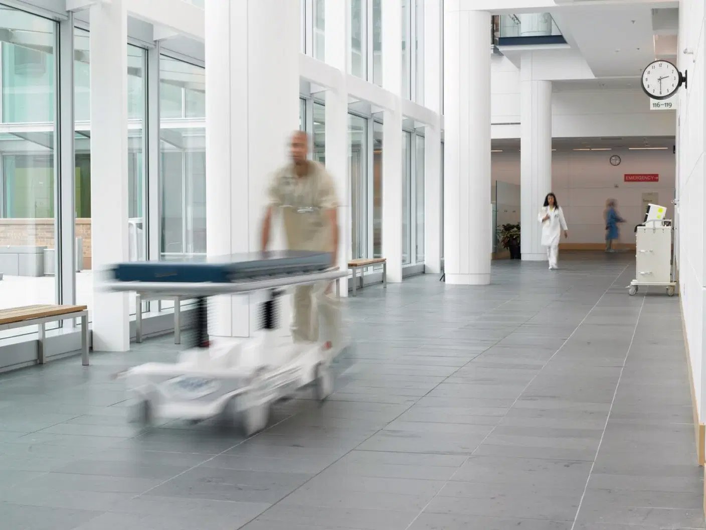 Healthcare professional transporting medical equipment through a hospital corridor.