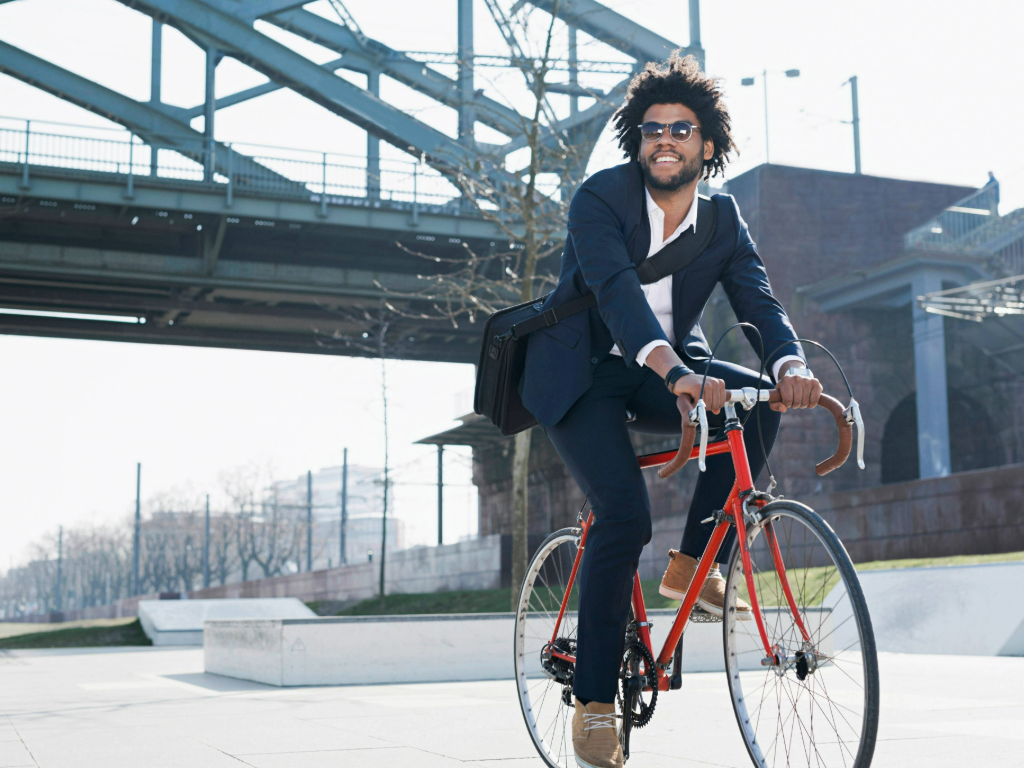 Mann im Anzug fährt mit einem roten Rennrad durch die Stadt.