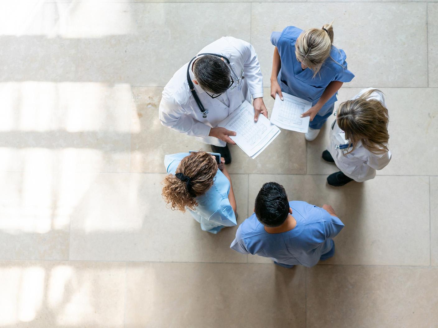 Overhead view of a physician and healthcare professionals reviewing patient charts and discussing clinical care.