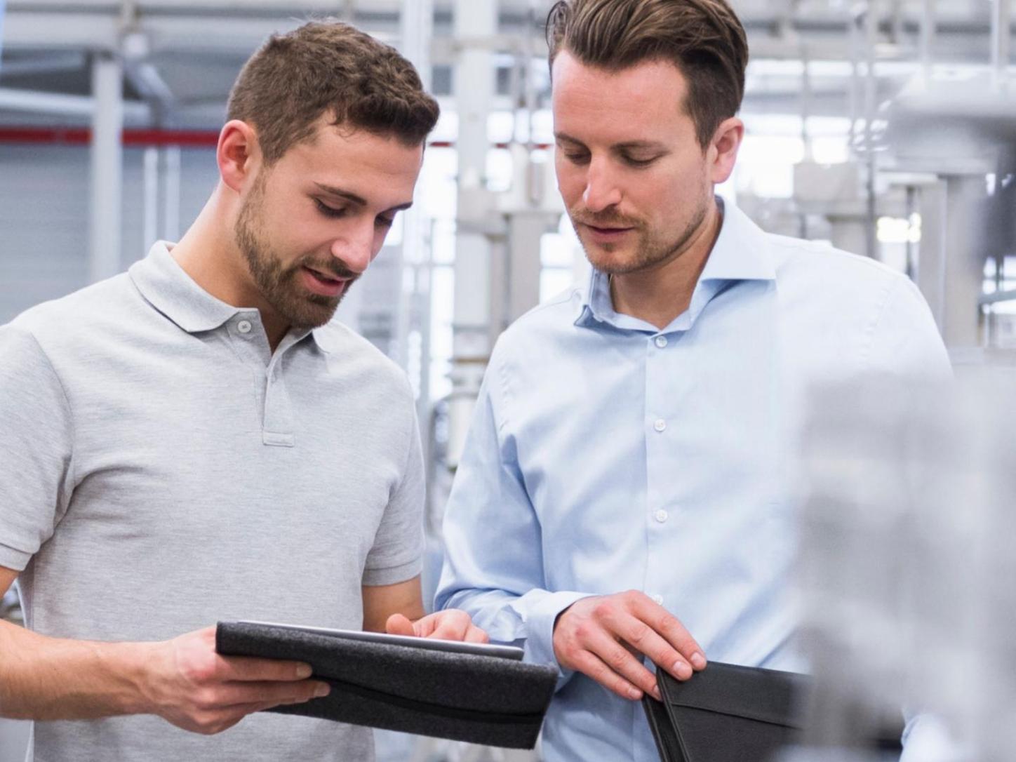 Two professionals reviewing information on a tablet in a healthcare facility.