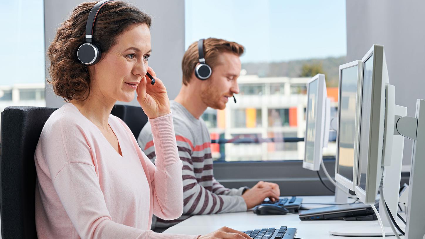 Remote Support desk with man and woman sitting in office looking at computers