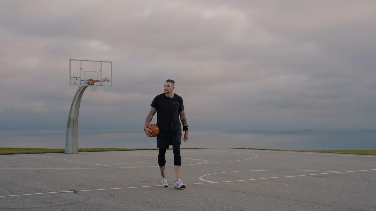 Picture showing Joe Buck, former professional basketball player, walking over a baseket ball court.