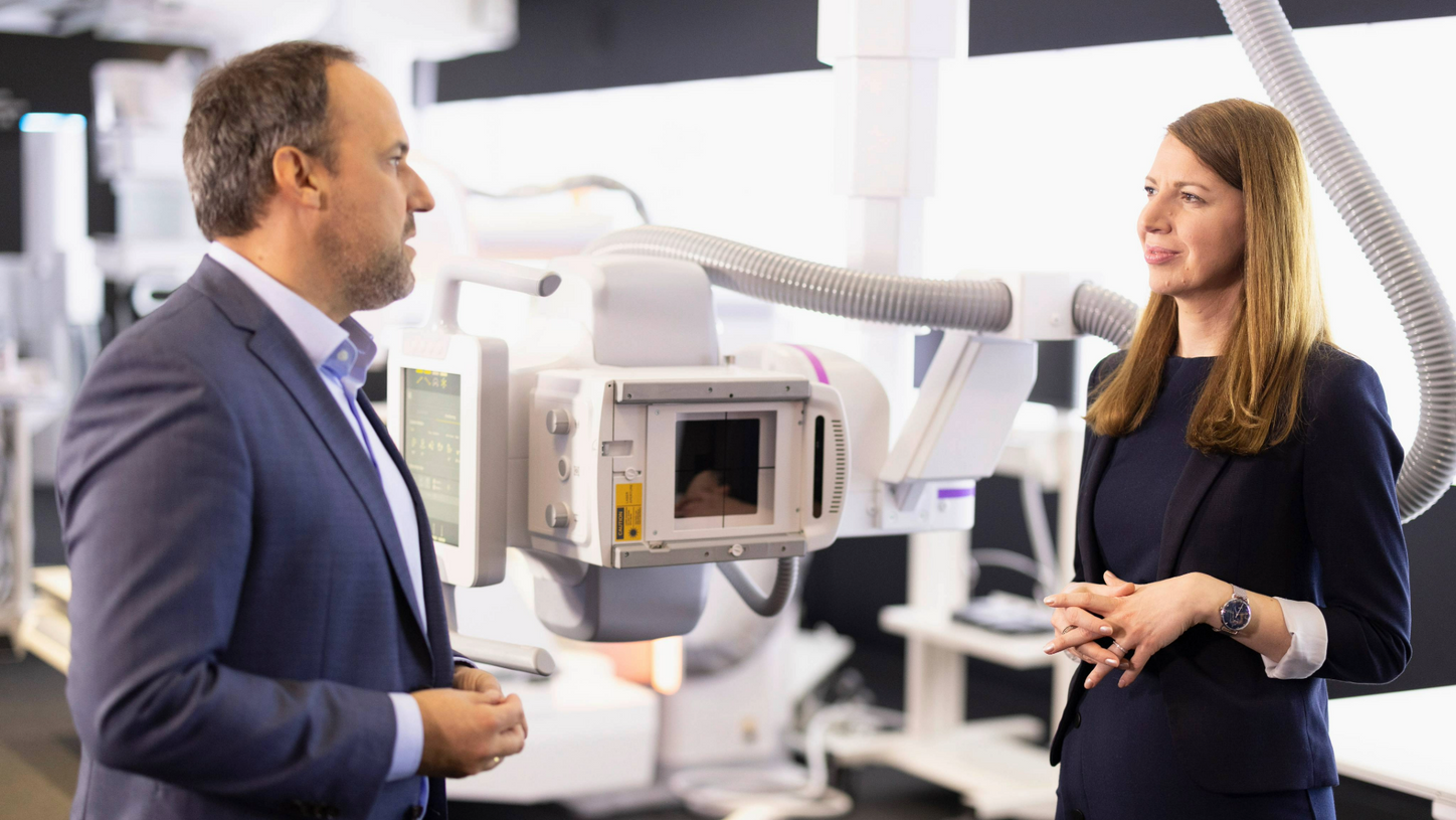 Ein Mann und eine Frau stehen auf Messe vor einem medizinischen Gerät.
