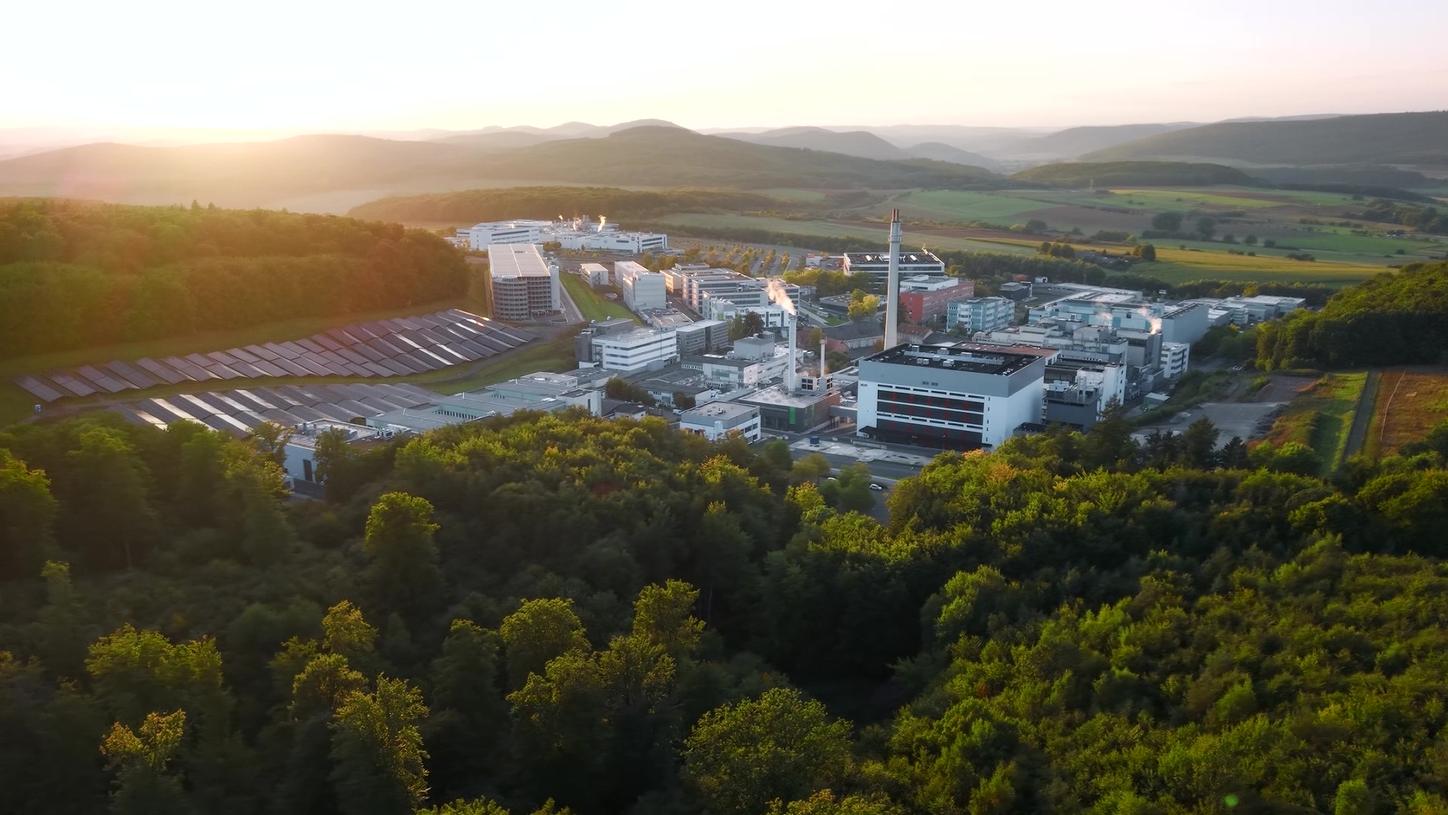 Aerial view of a Siemens Healthineers facility surrounded by wooded hills and countryside.
