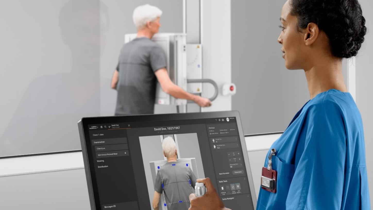 Radiology technician using a computer to position a patient for a chest X-ray.