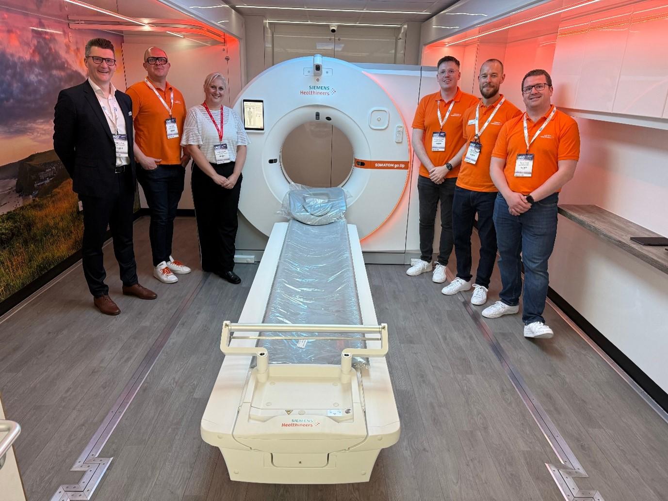 [From left to right] Graham Plant – head of diagnostic imaging, Carl Smith – business area lead for CT at Siemens Healthineers Great Britain and Ireland, Denise Taljaard – sales executive at WH Bence, Matthew Whitfield – CT product specialist, Luke Walton – CT product specialist, and Conor Casey – CT product specialist at Siemens Healthineers Great Britain and Ireland, standing inside the UK’s first hybrid-powered mobile CT unit next to the SOMATOM go.Up CT system.