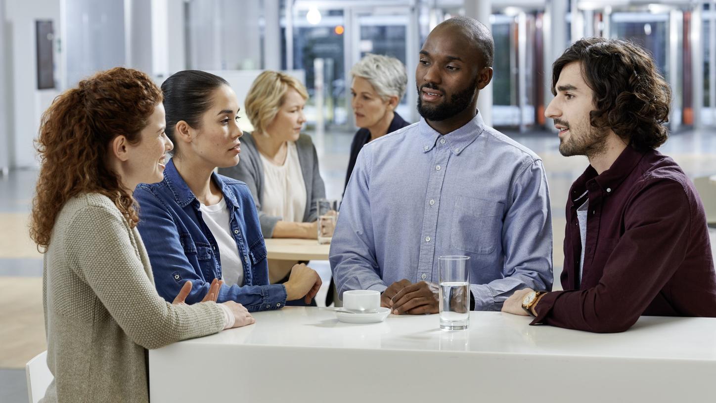 A diverse group of professionals engaged in a friendly discussion at a modern office lounge