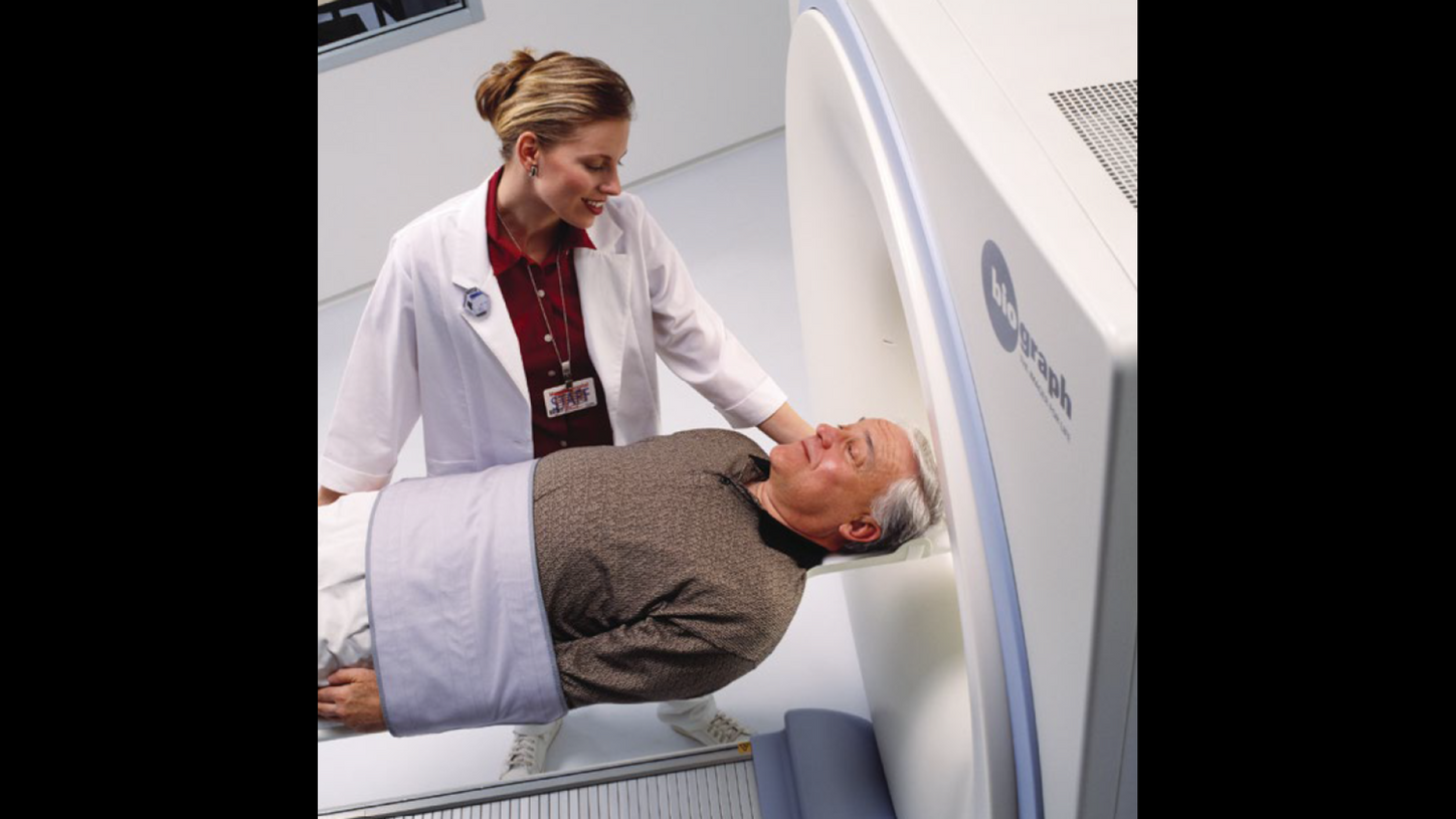 Hospital staff guiding an old patient through the Biograph PET/CT Scanner