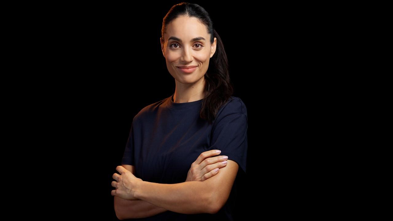 Confident healthcare professional with arms crossed against black background