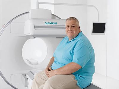 Obese female patient on sitting on SPECT scanner bed